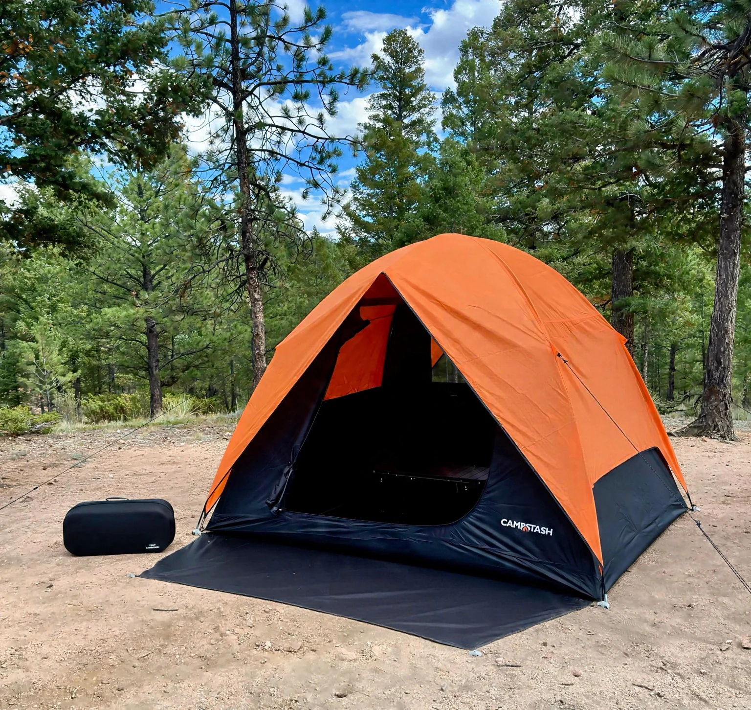 Campstash Tent with its orange rainfly and molded case at a forest campsite